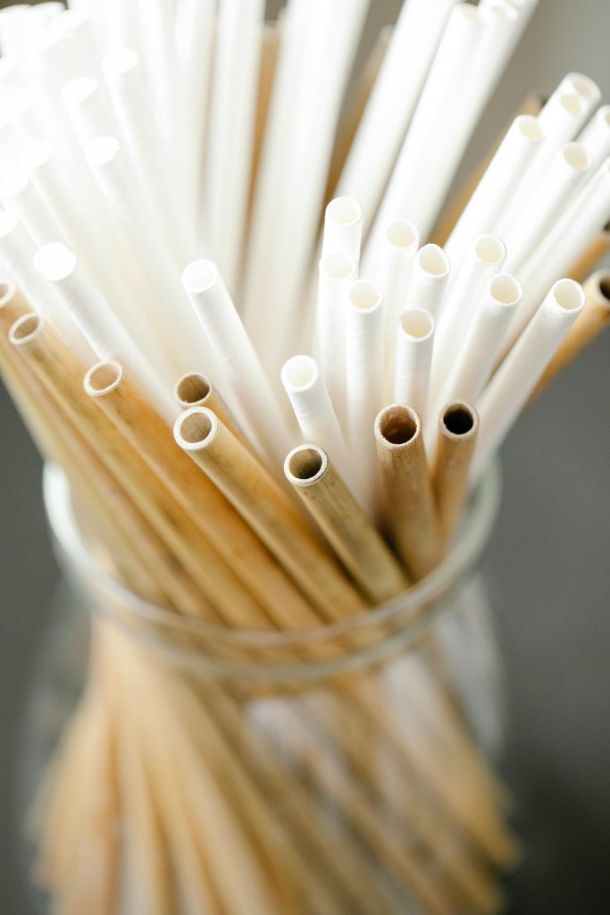 Close-up of eco-friendly disposable bamboo and paper straws in a glass jar.